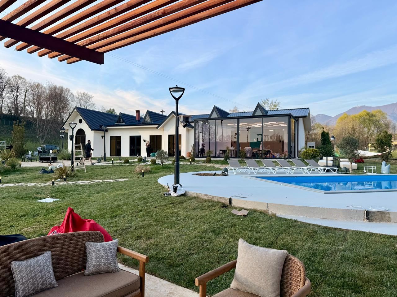 View from the pergola toward the house, showing the pool, garden, and main volume of Ferma VIP