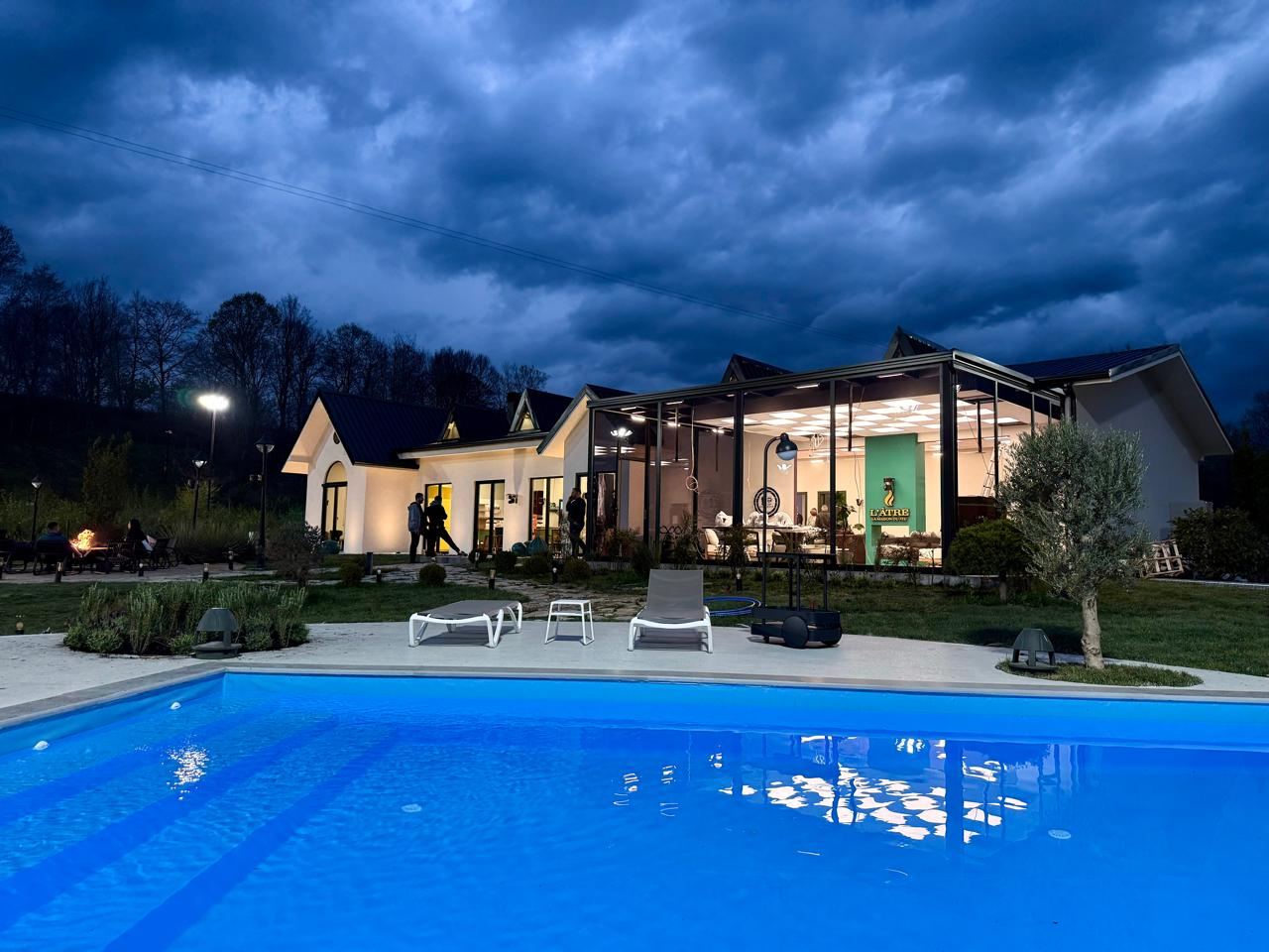 Ferma VIP at dusk, illuminated house and pergola reflected in the pool under a dramatic evening sky