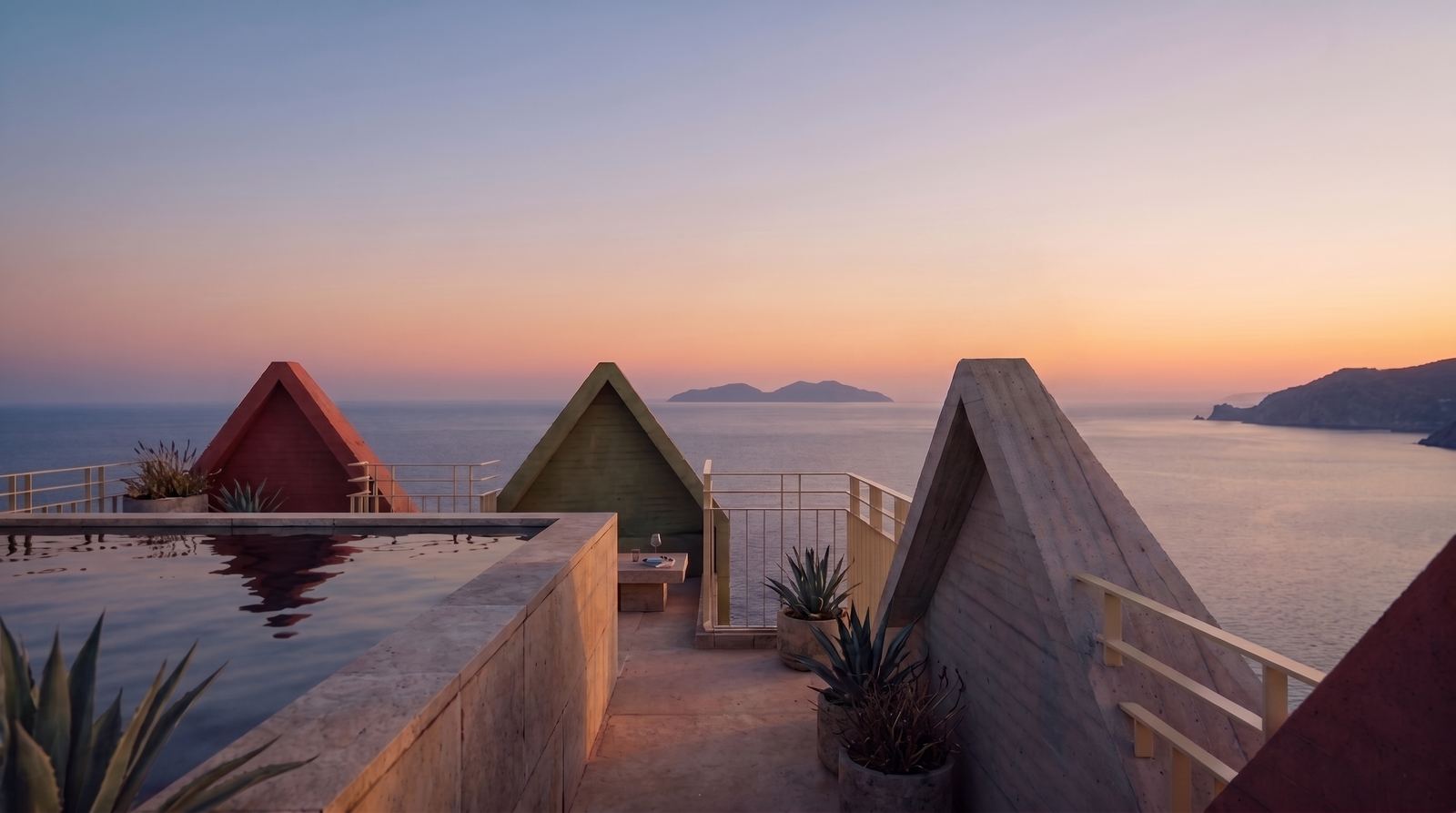 Rooftop infinity pool and triangular architectural pavilions overlooking the sea at sunset.